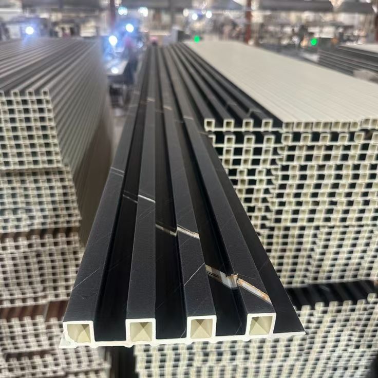 PVC fluted wall panels manufacturing and stock — black solid color grille panels with hollow WPC channel core at the factory